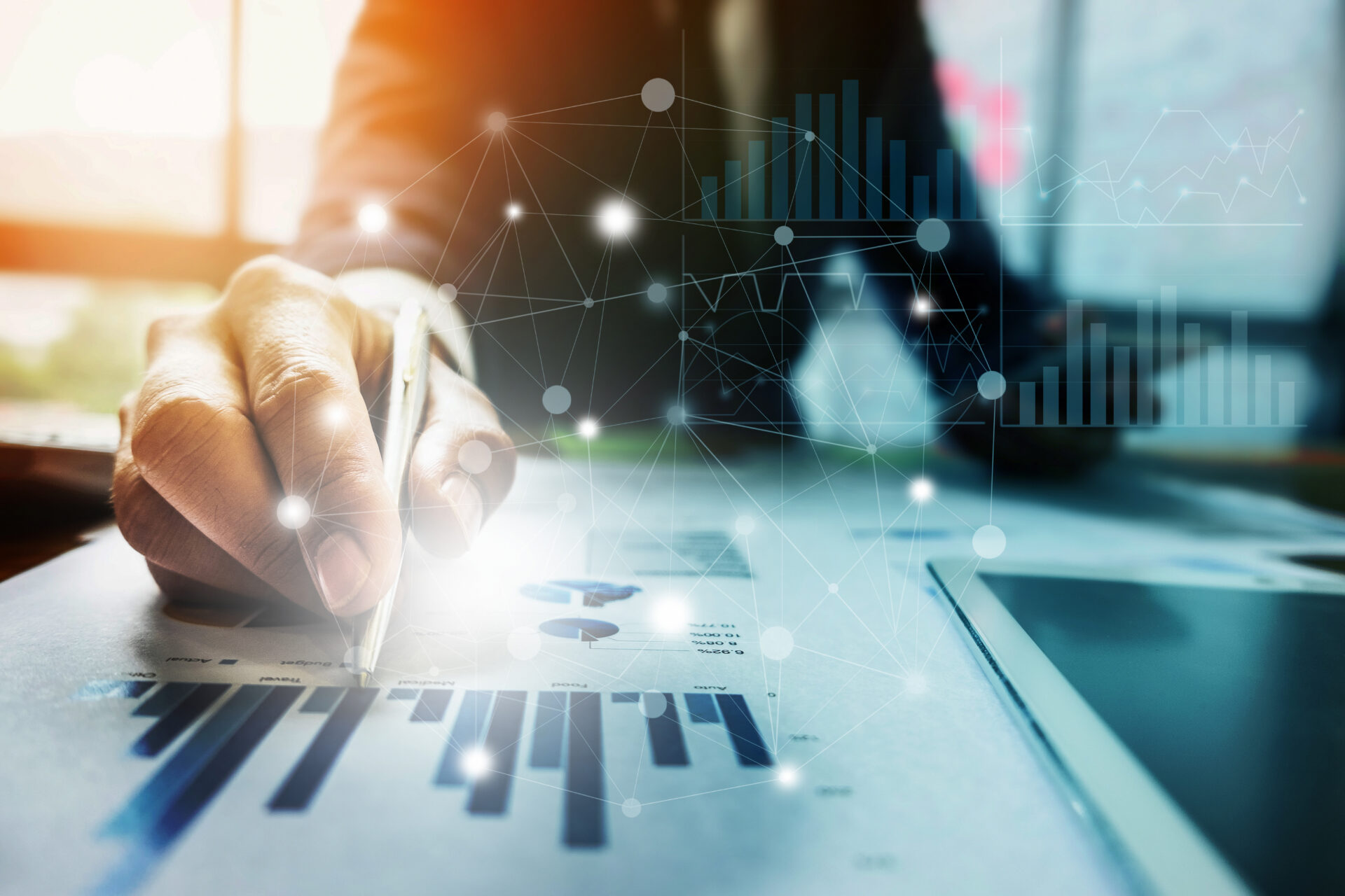 Close up Businessman hand holding pen and pointing at financial paperwork with financial network diagram.